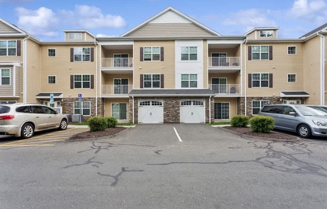 A parking lot in front of a large apartment building with two cars parked.