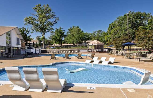 A pool with white chairs and a building in the background.