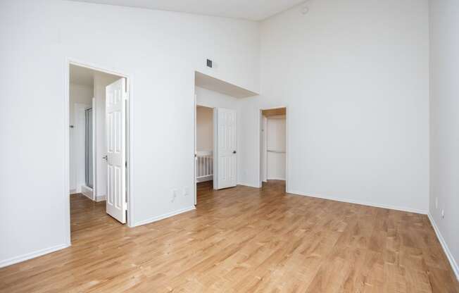 an empty living room with wood floors and white walls