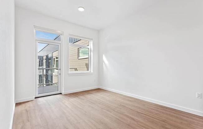 a living room with white walls and a door to a balcony