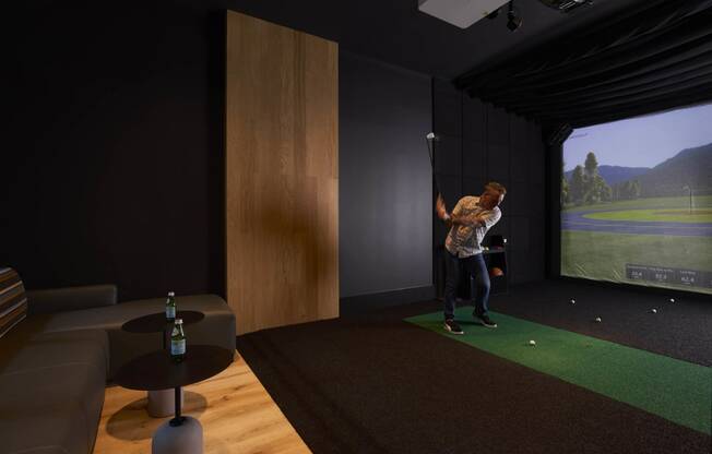 a man playing golf on a simulator in a living room