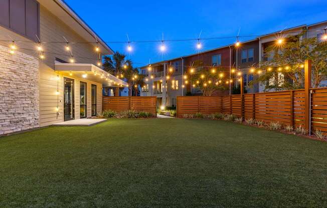 A well-lit outdoor area with a grassy lawn and a building in the background.