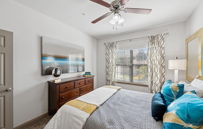 A bedroom with a bed, dresser, and a ceiling fan.
