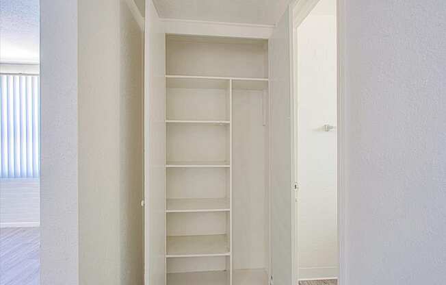 a walk in closet in a bedroom with white walls and white shelves