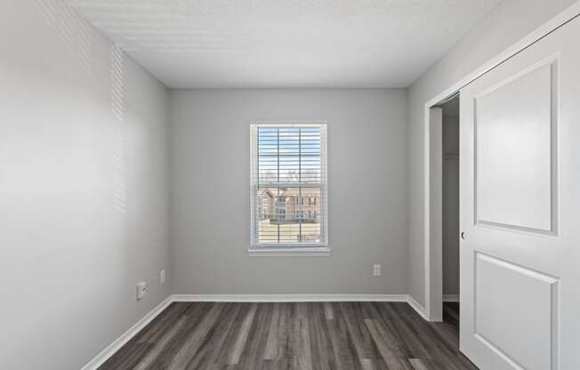 an empty living room with wood flooring and a window