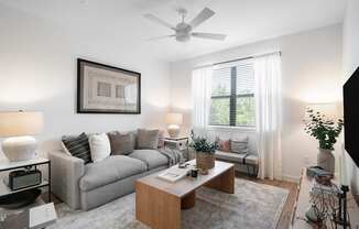 A living room with a grey couch, a wooden coffee table, and a ceiling fan.