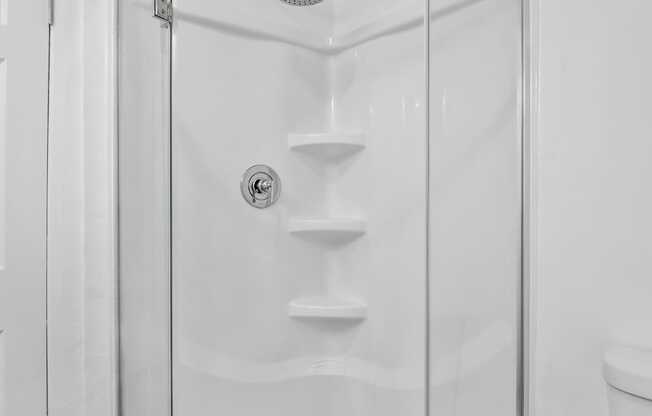 A white bathroom with a walk in shower at Verandas Apartments, West Covina, California