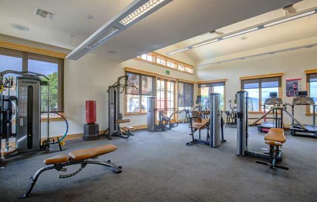 a large fitness room with exercise equipment and windows