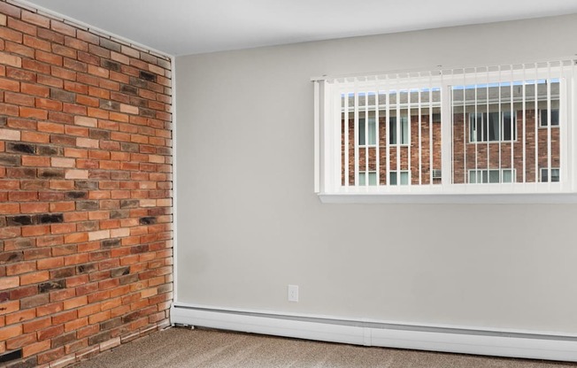 A room with a brick wall and a window with blinds.
