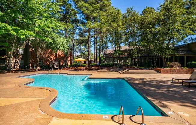 a swimming pool with trees and a building in the background at The Summit Apartments, Memphis, TN, 38128