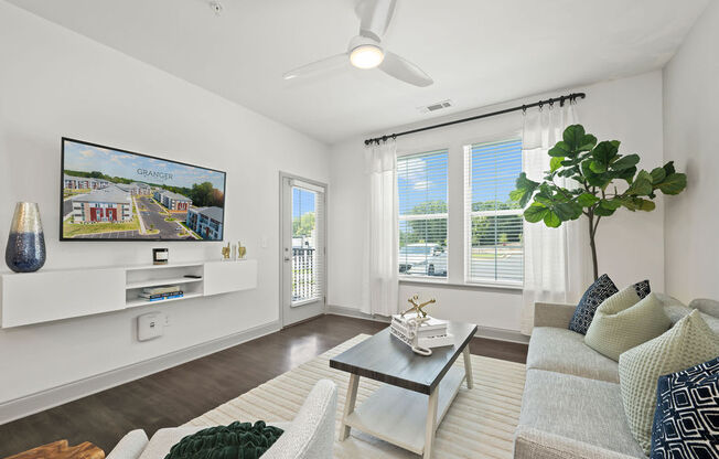 a living room with a couch coffee table and a tv on the wall