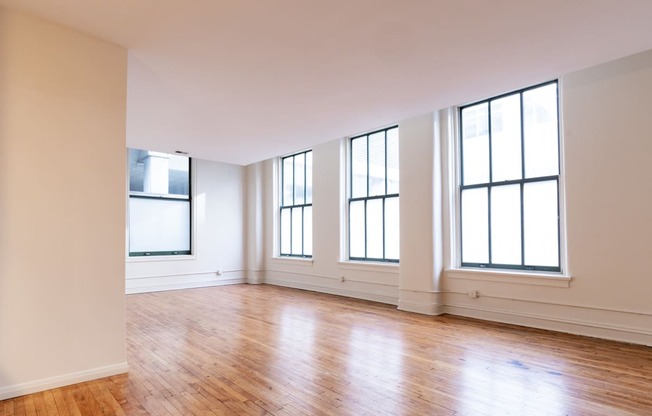 an empty living room with white walls and wood floors at 26 West, Managed by Buckingham Urban Living, Indianapolis