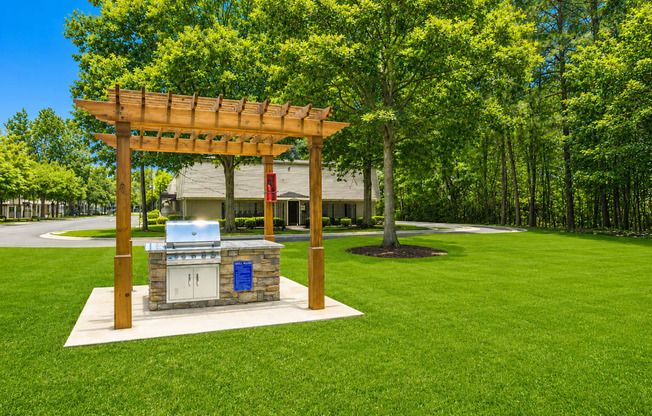 A wooden pergola with a grill on a patio.