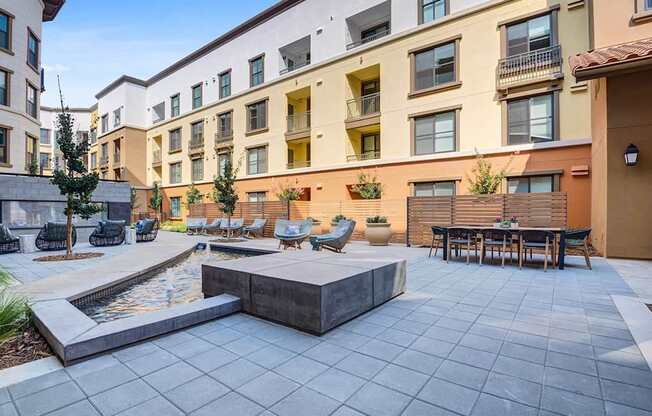 A courtyard with a fountain and seating area surrounded by apartment buildings.