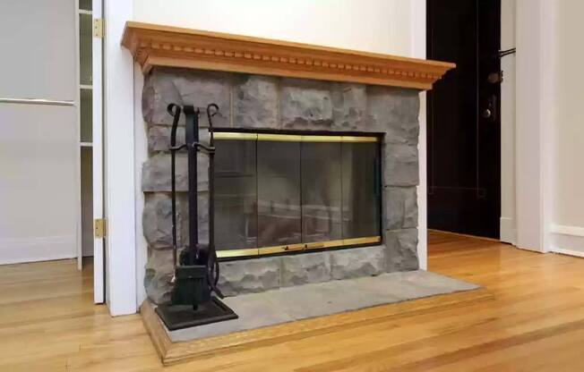 a stone fireplace in a living room with a wood floor at The Bryant at Oak Park I & II, Oak Park, IL 60302