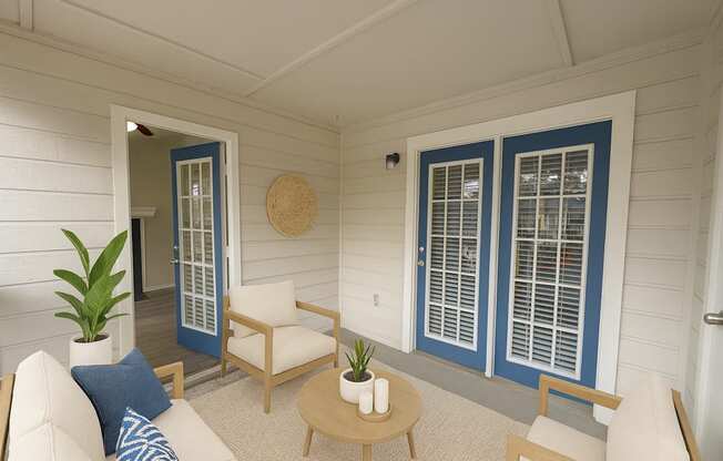 A white couch with blue pillows sits in a sunroom with a white ceiling and a blue door.