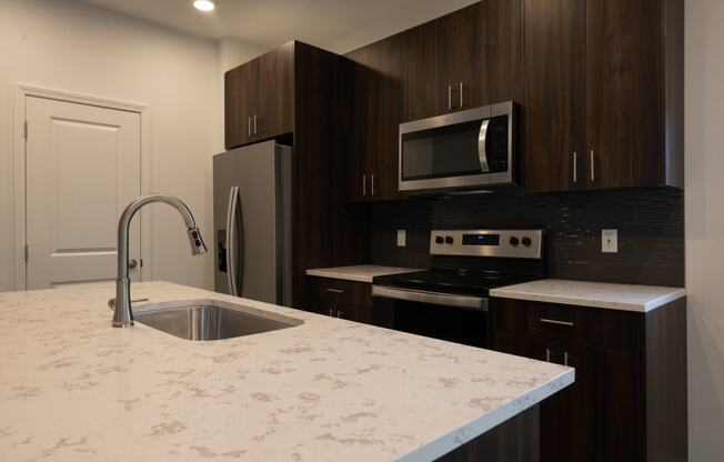 a kitchen with a marble counter top and a sink at The Clearing at ONE28, Olathe, 66062