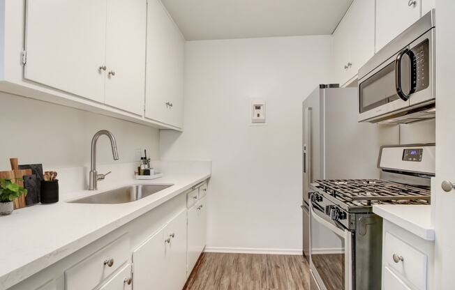 a white kitchen with stainless steel appliances and white cabinets