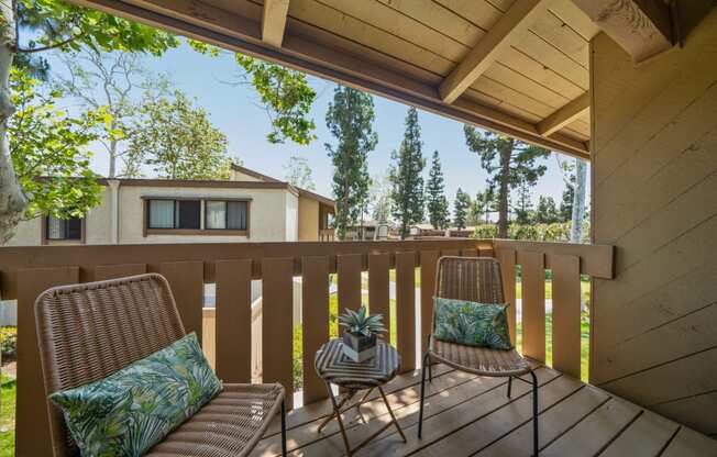 two chairs on a deck with a house in the background