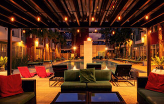 Outdoor lounge at The Mercer luxury apartments near Summerlin with modern seating, warm string lights, and resort-style pool featuring fire element.