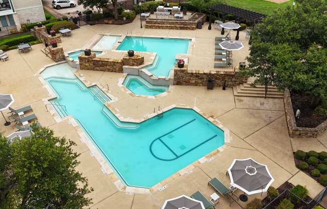 a pool and spa are shown in a backyard with tables and umbrellas