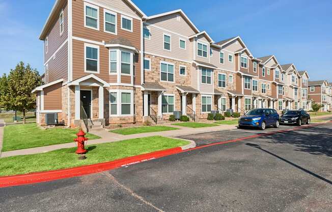 A row of apartment buildings with a red fire hydrant in front of the first one.