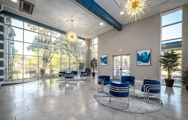 a lobby with blue chairs and large windows and a chandelier