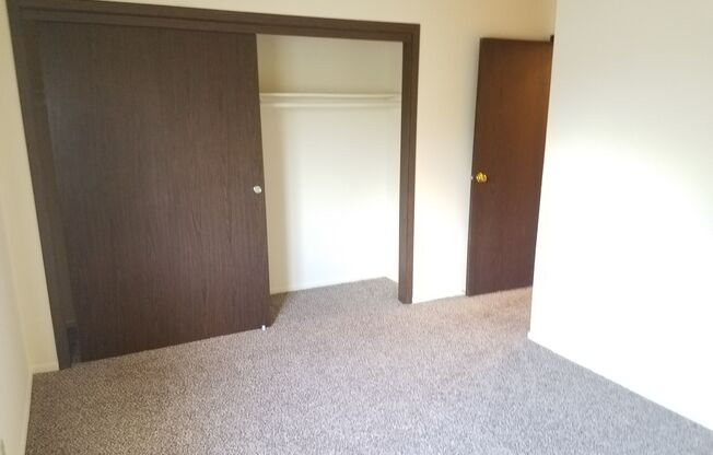 A room with a carpeted floor and two doors.