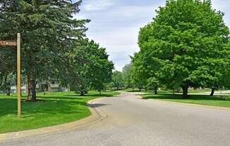 a street with trees on both sides and a street sign in the middle of the road