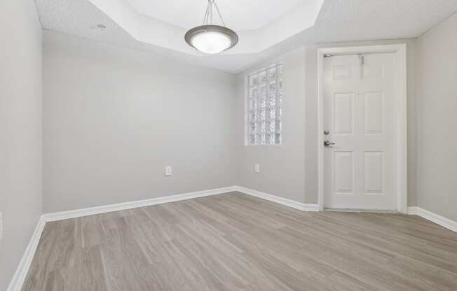 an empty living room with a white door and wood flooring at Pembroke Pines Landings, Pembroke Pines 