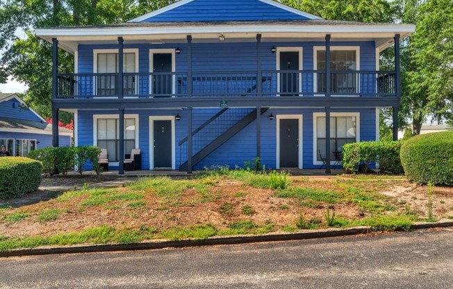 a blue house with a porch and a street in front of it