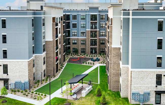 A large apartment complex with a green lawn in the middle.