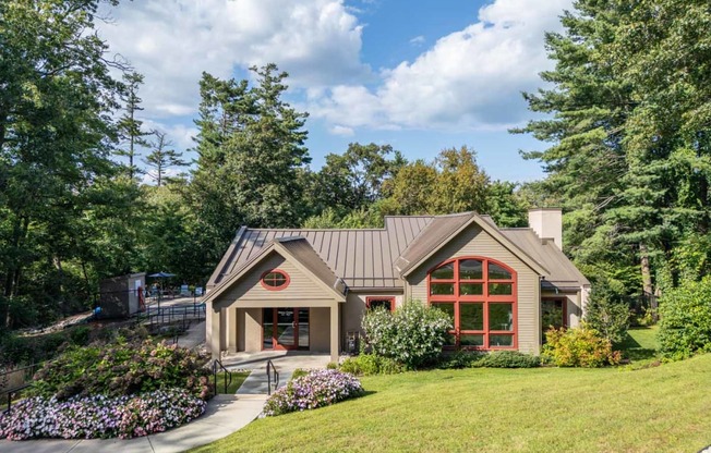 the front of a house with a lawn and trees