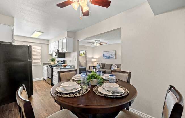 A dining room with a table set for two and a ceiling fan.