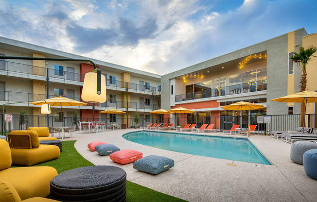 a swimming pool with lounge chairs and umbrellas in front of a building