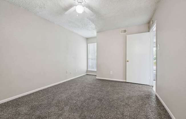 A room with a carpeted floor and a ceiling fan.