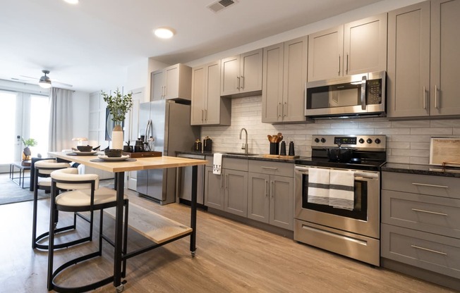 a kitchen with gray cabinets and stainless steel appliances