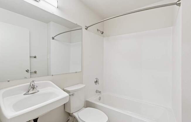 A white bathroom with a toilet, sink, and bathtub.