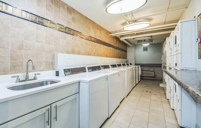 A clean, well-equipped commercial kitchen with white appliances and a tiled floor.
