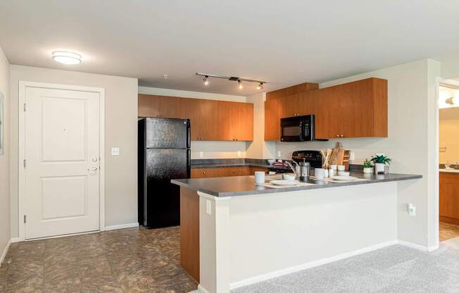 A kitchen with a black fridge and wooden cabinets.