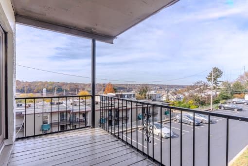 the balcony has a view of the parking lot and the city