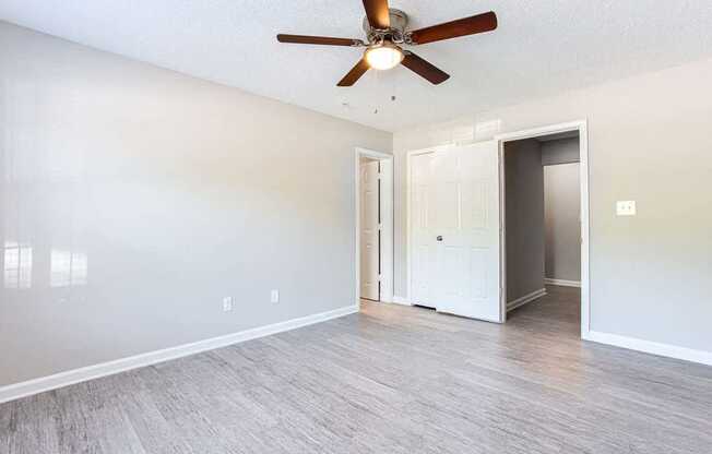 A room with a ceiling fan and light fixture, two doors, and a wall-mounted light switch.