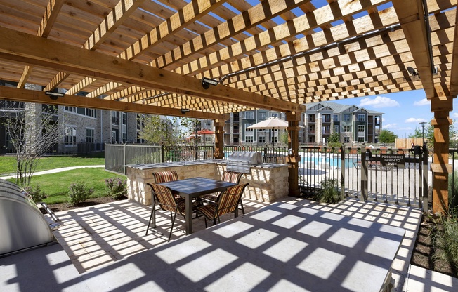 a patio with a table and chairs under a wooden pergola at North Creek, Hutto, TX