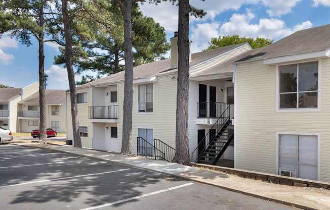 A row of apartment buildings with trees in front.