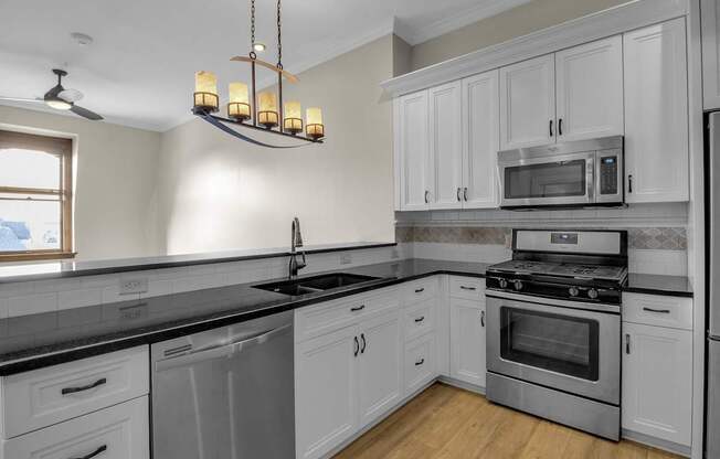 a kitchen with stainless steel appliances and white cabinets at The Knights @ 506 Delaware Apartments, Buffalo, NY 14202