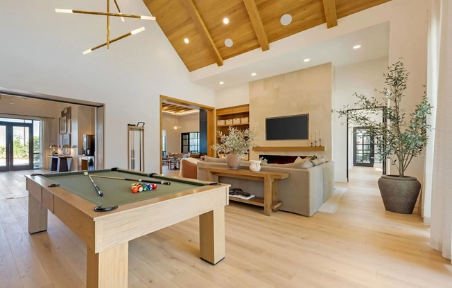 A pool table is in the middle of a spacious room with a television and a couch.