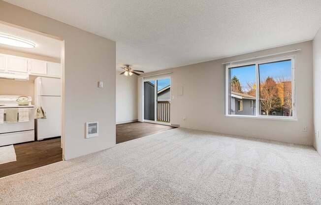 A spacious living room with a carpeted floor and a large window.