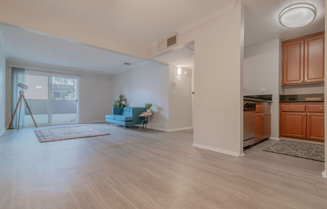 an open living room with a kitchen and a door to a balcony at City View Apartments at Warner Center, Woodland Hills