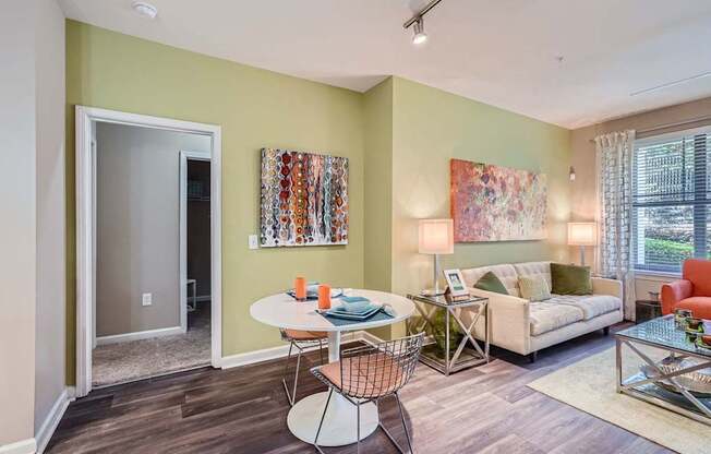 A living room with a white table and chairs, a couch, and a painting on the wall.