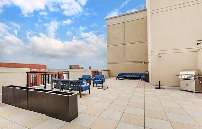 a rooftop patio with a grill and tables and benches